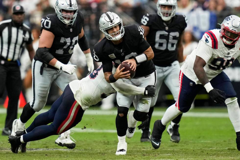 Las Vegas Raiders quarterback Jimmy Garoppolo, center, is hauled down by New England Patriots l ...