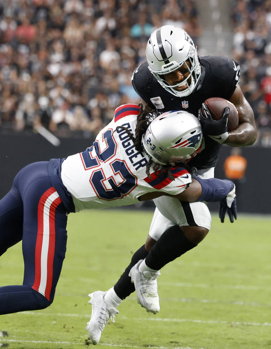 Raiders running back Josh Jacobs (8) tackled by New England Patriots safety Kyle Dugger (23) du ...