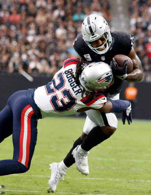 Raiders running back Josh Jacobs (8) tackled by New England Patriots safety Kyle Dugger (23) du ...