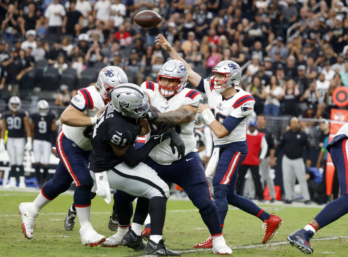 New England Patriots quarterback Mac Jones (10) throws under pressure from Raiders defensive ta ...