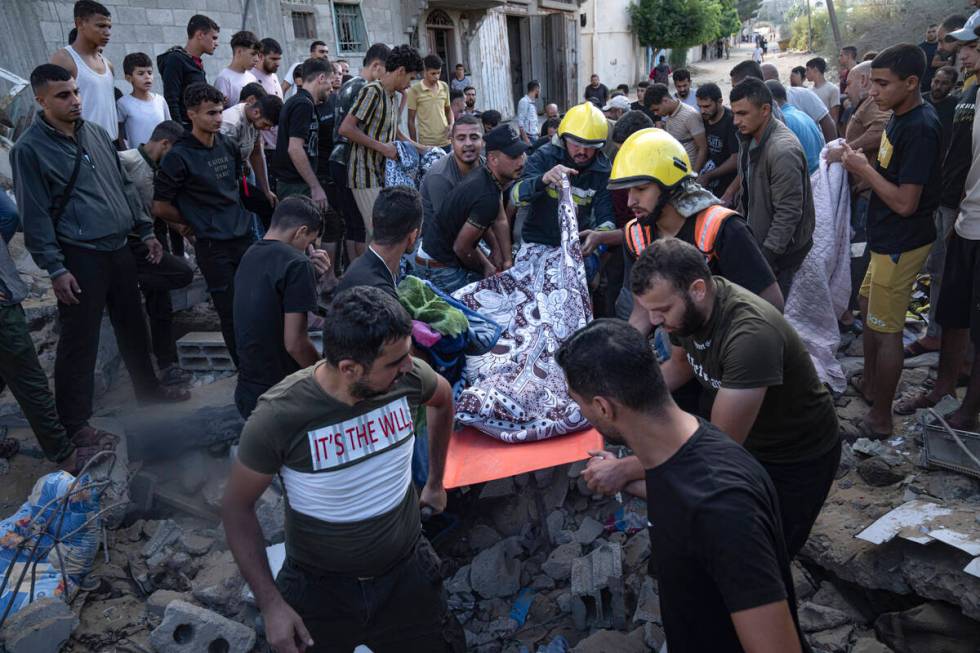 Palestinians carry a person wounded in Israeli airstrikes in Khan Younis, Gaza Strip, Monday, O ...