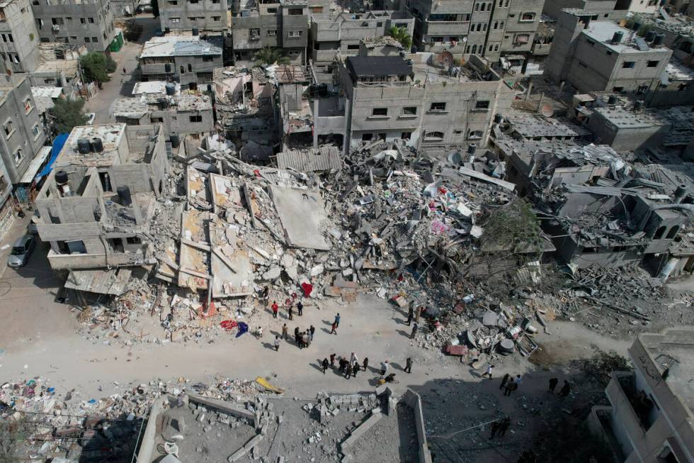 Palestinians stand by the building destroyed in an Israeli airstrike in Nuseirat camp in the ce ...