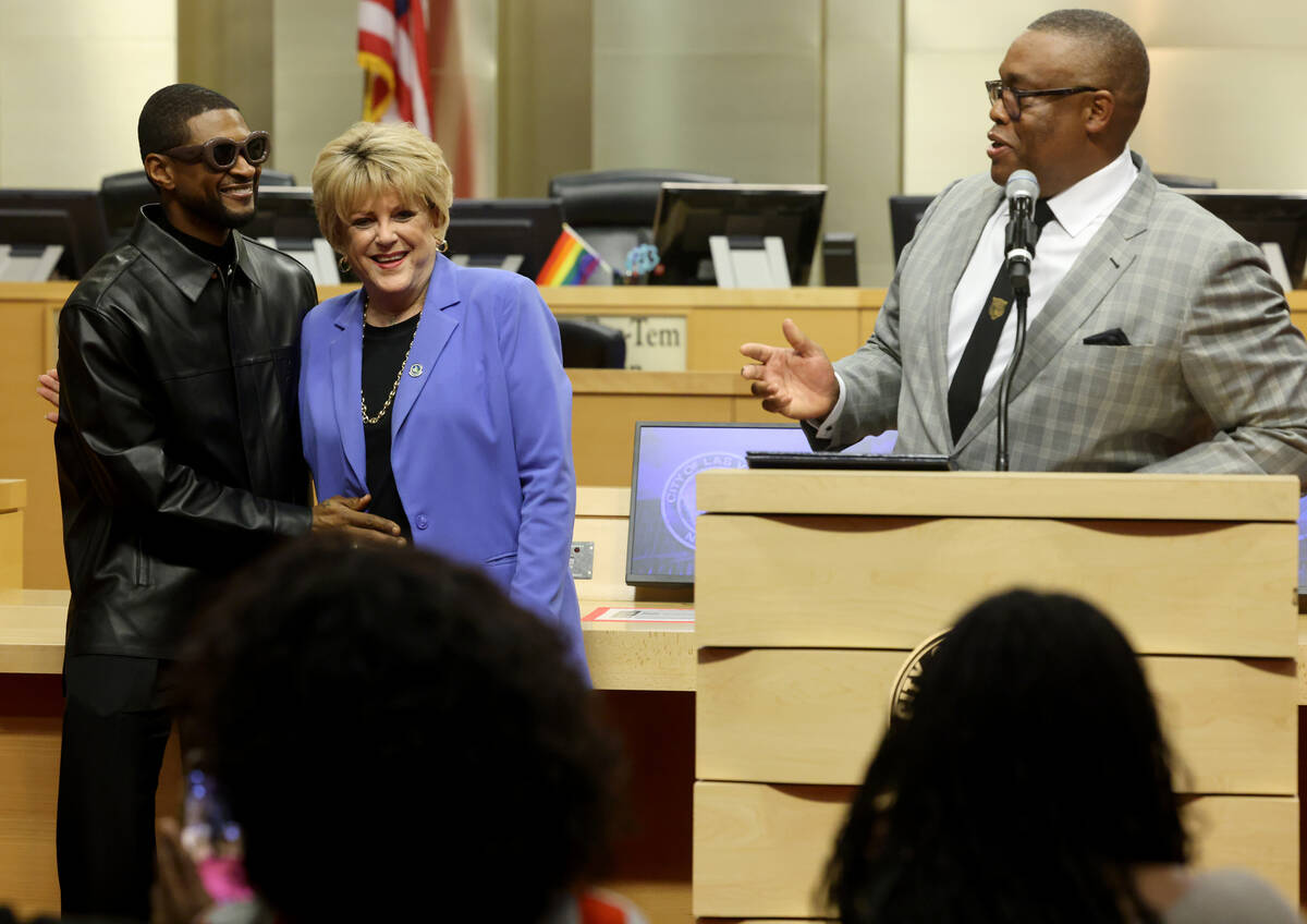 Usher, left, hugs Las Vegas Mayor Carolyn Goodman as Councilman Cedric Crear speaks at City Hal ...