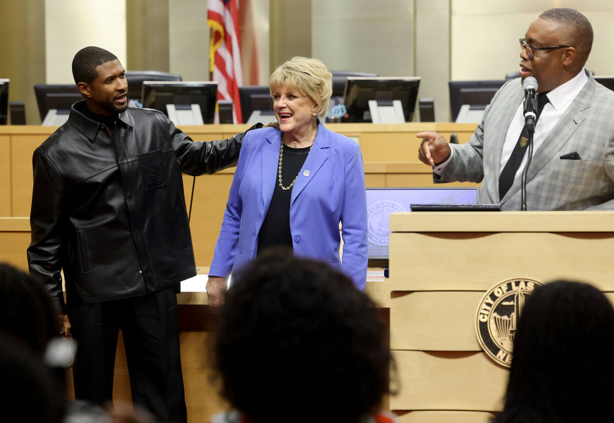 Usher, left, hugs Las Vegas Mayor Carolyn Goodman as Councilman Cedric Crear speaks at City Hal ...