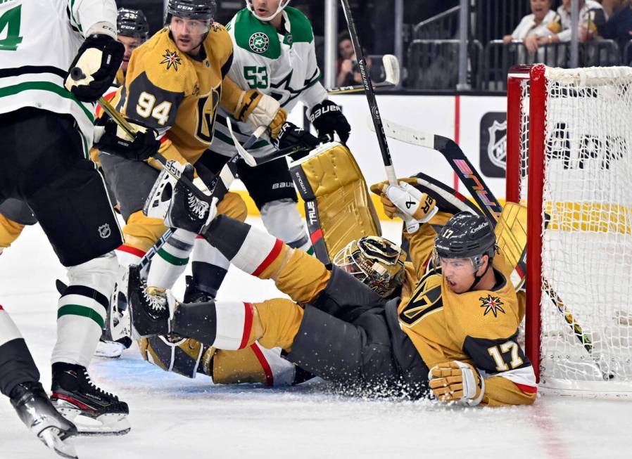 Vegas Golden Knights defenseman Ben Hutton (17) falls into the goal with goaltender Adin Hill d ...