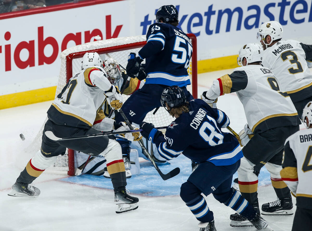 Vegas Golden Knights goaltender Logan Thompson, second from left, saves the shot from Winnipeg ...