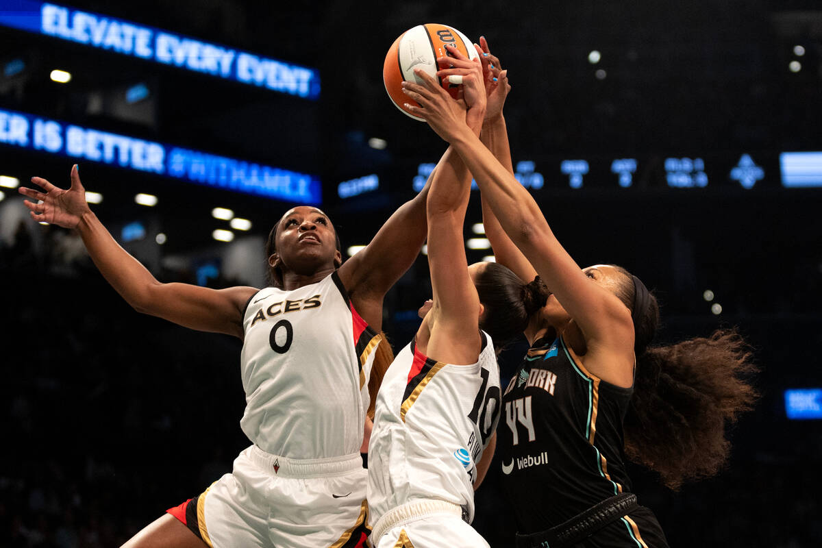 Las Vegas Aces guard Jackie Young (0) and guard Kelsey Plum (10) jump to block a shot by New Yo ...