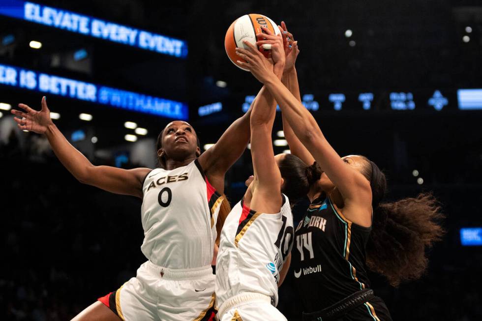 Las Vegas Aces guard Jackie Young (0) and guard Kelsey Plum (10) jump to block a shot by New Yo ...