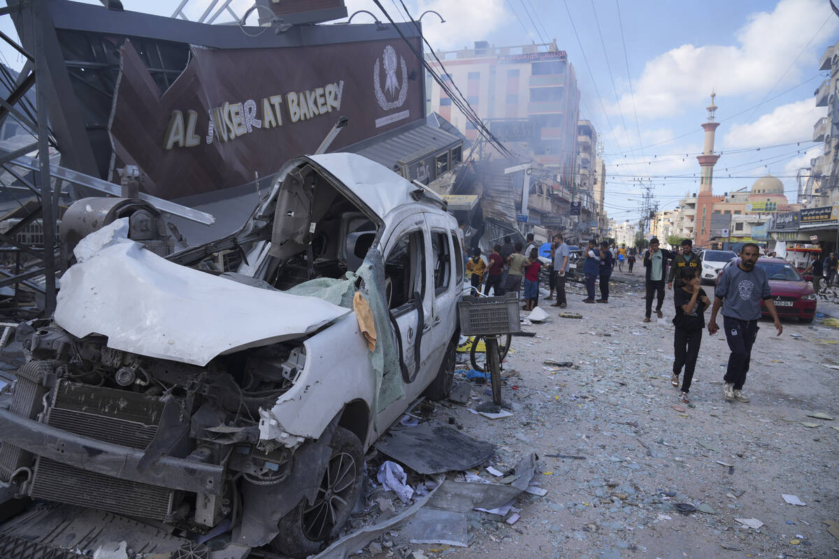 Palestinians walk by the destroyed building of Al Nuseirat Bakery in an Israeli airstrike Nusse ...