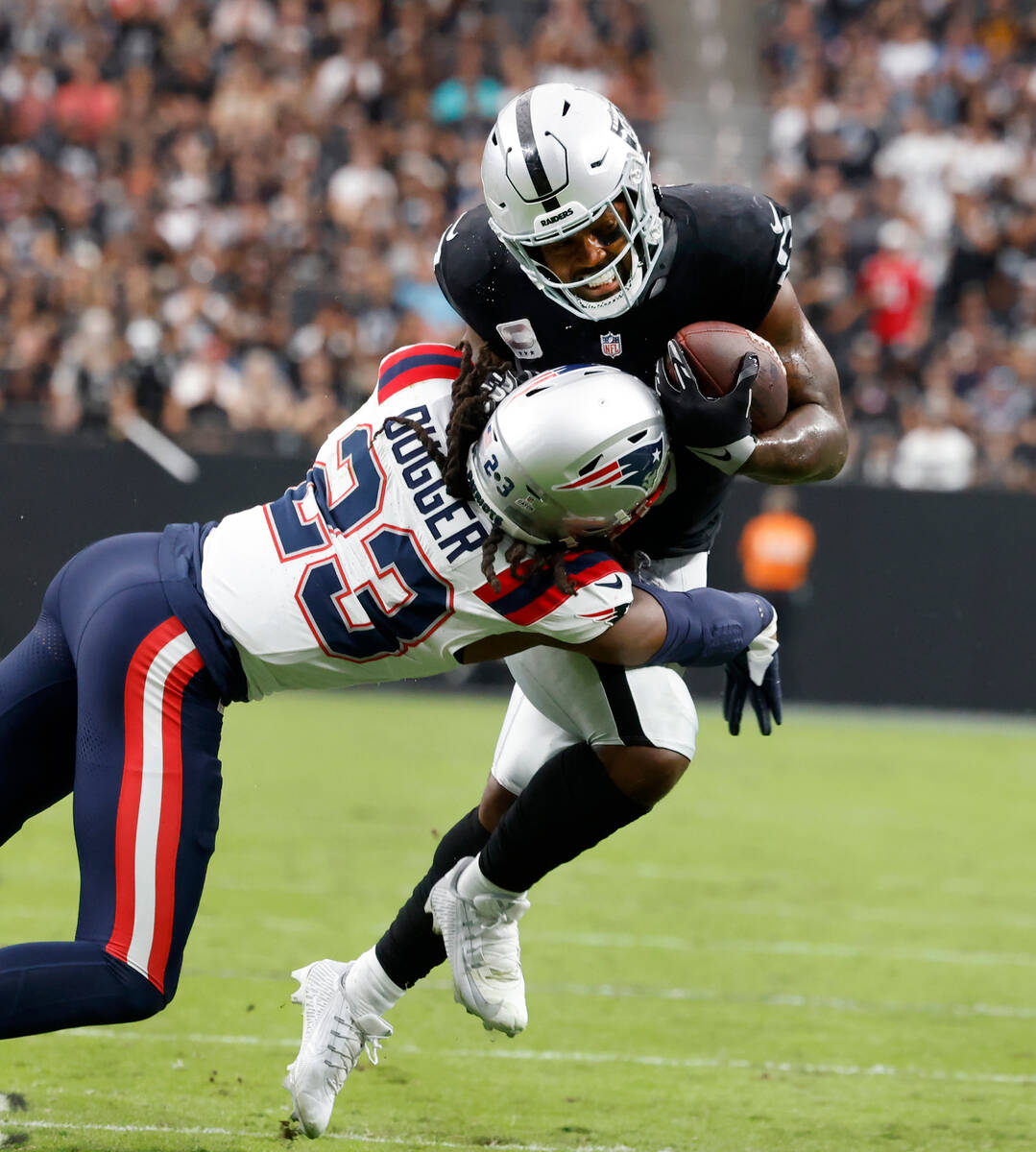 Raiders running back Josh Jacobs (8) tackled by New England Patriots safety Kyle Dugger (23) du ...