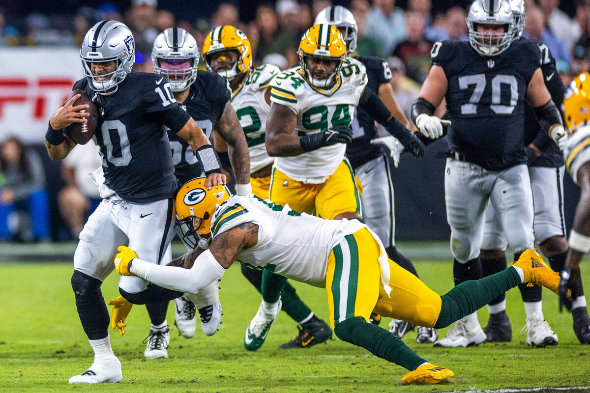 Raiders quarterback Jimmy Garoppolo (10) is grabbed on a run by Green Bay Packers linebacker Pr ...
