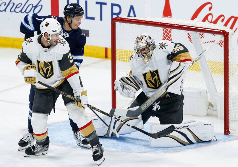 Vegas Golden Knights goaltender Logan Thompson (36) saves a shot as teammate Brayden McNabb (3) ...