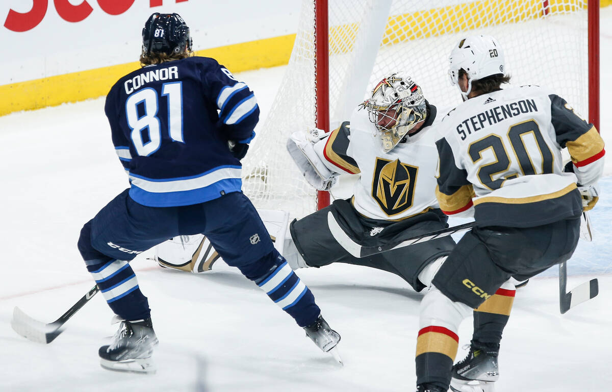 Vegas Golden Knights goaltender Logan Thompson, center, saves the shot from Winnipeg Jets' Kyle ...