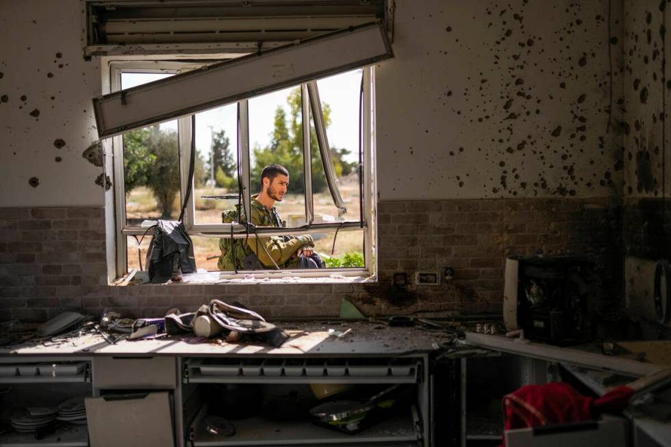 An Isreal soldier patrols next to a house damaged by Hamas militants at Kibbutz Kissufim in sou ...