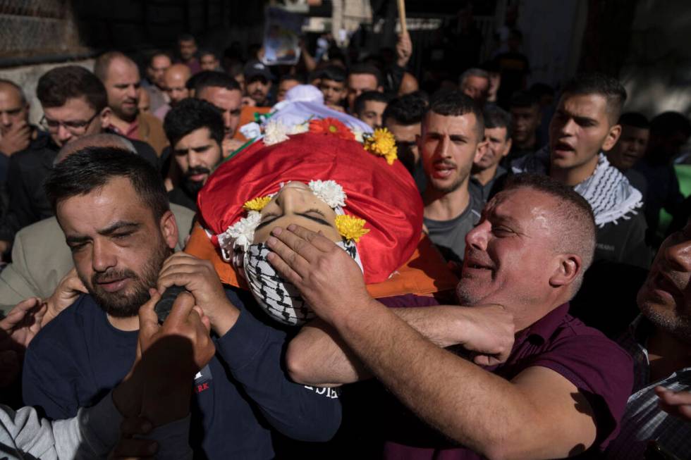 Eyad al-Soos, right carries the body of his son Sohaib al-Soos, 15, during his funeral in the W ...