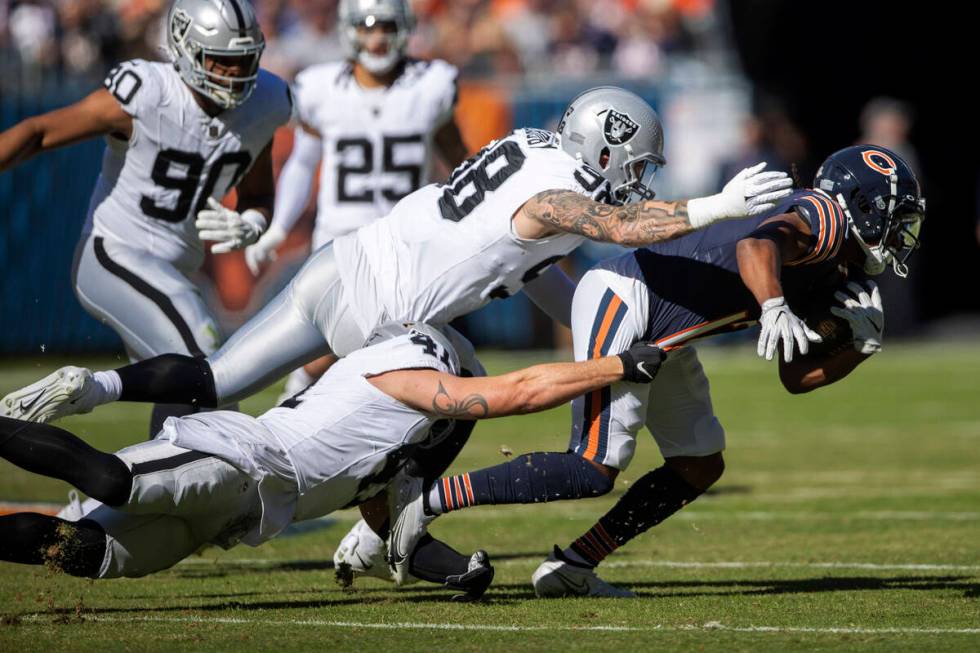 Raiders linebacker Robert Spillane (41) and defensive end Maxx Crosby (98) extend to tackle Chi ...