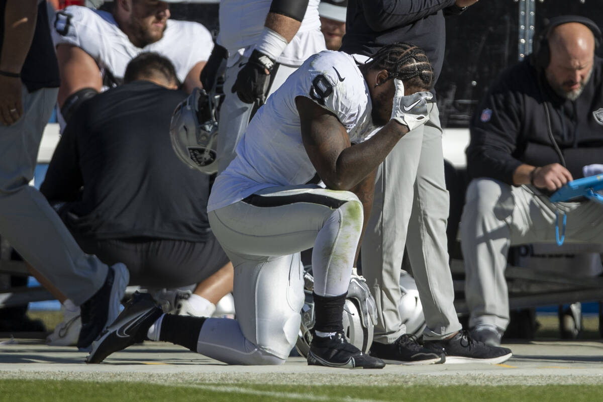 Raiders running back Josh Jacobs (8) holds his head in his hand on the sideline during the seco ...