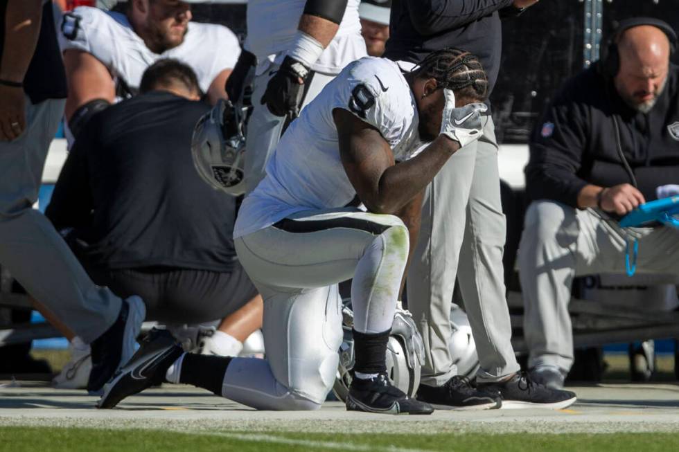 Raiders running back Josh Jacobs (8) holds his head in his hand on the sideline during the seco ...