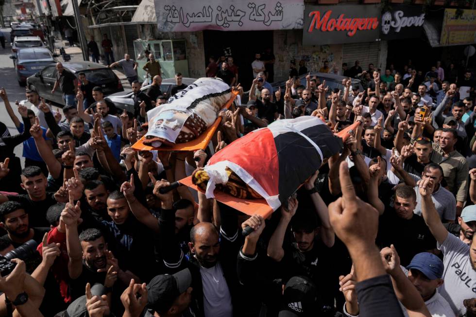 Palestinians carry the bodies of Muhammed Hussein, draped in the Palestinian flag and Muhammad ...