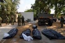 Israeli soldiers stand next to the bodies of Israelis killed by Hamas militants in kibbutz Kfar ...