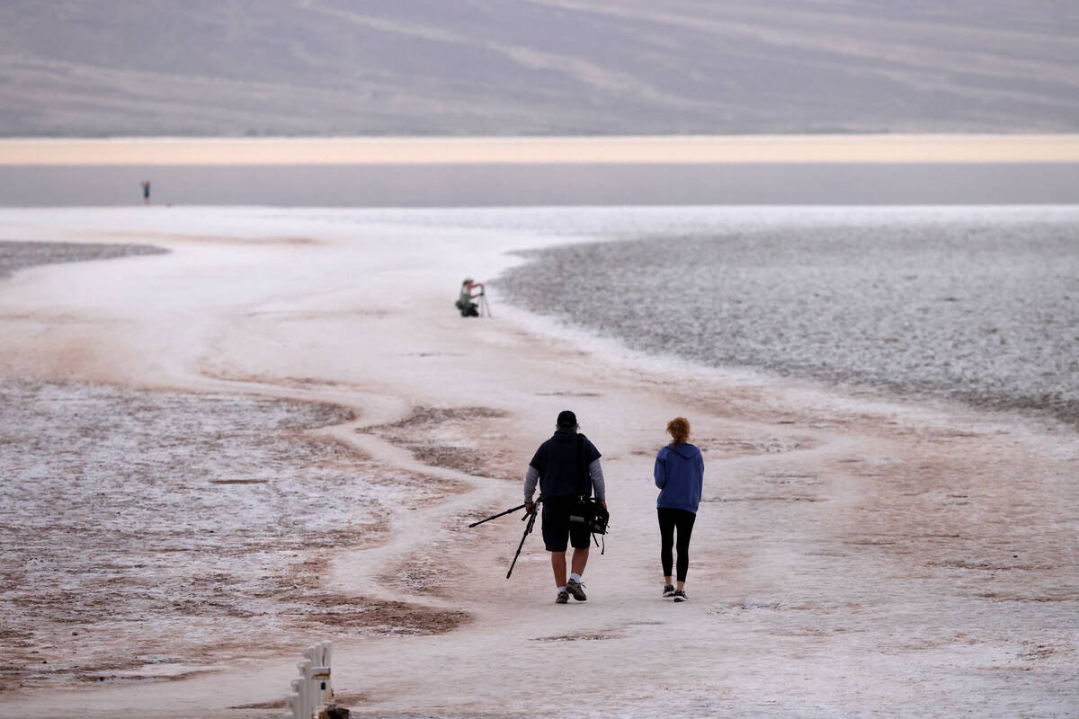 Visitors check out a rare lake in Badwater Basin in the recently reopened Death Valley National ...