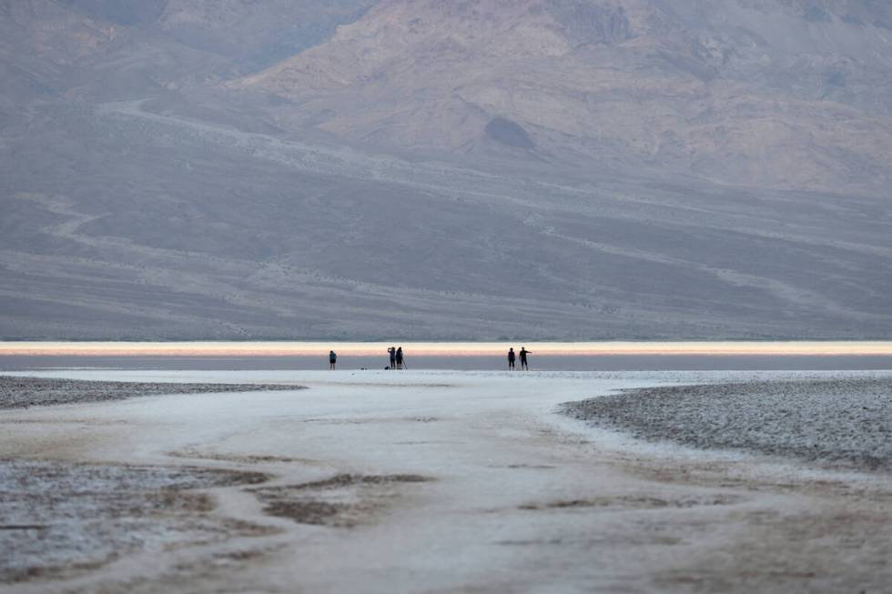 Visitors check out a rare lake in Badwater Basin in the recently reopened Death Valley National ...