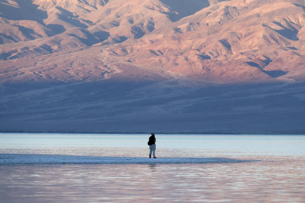 A visitor checks out a rare lake in Badwater Basin in the recently reopened Death Valley Nation ...