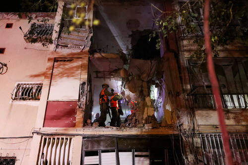 Israeli soldiers inspect the damage of a residential building after it was hit by a rocket fire ...