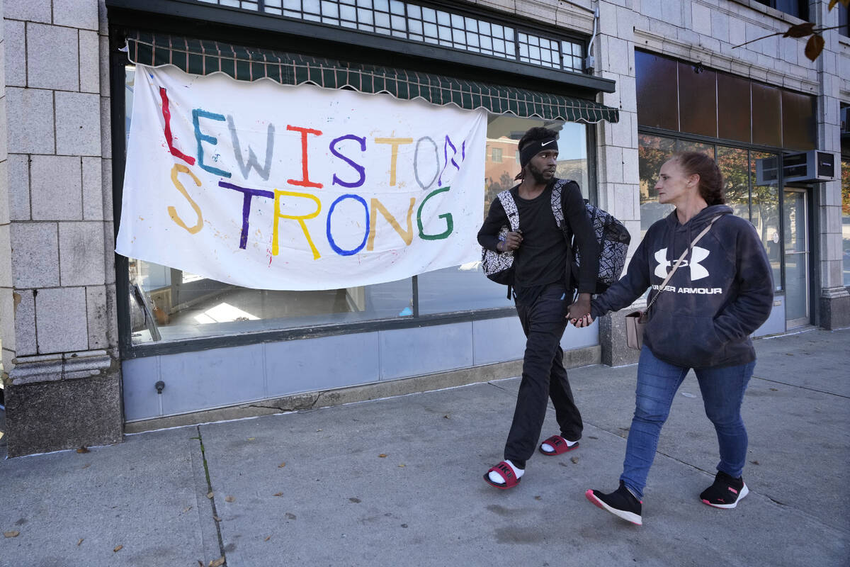 A couple walks by a banner that was put up in response to this week's deadly mass shootings, Fr ...