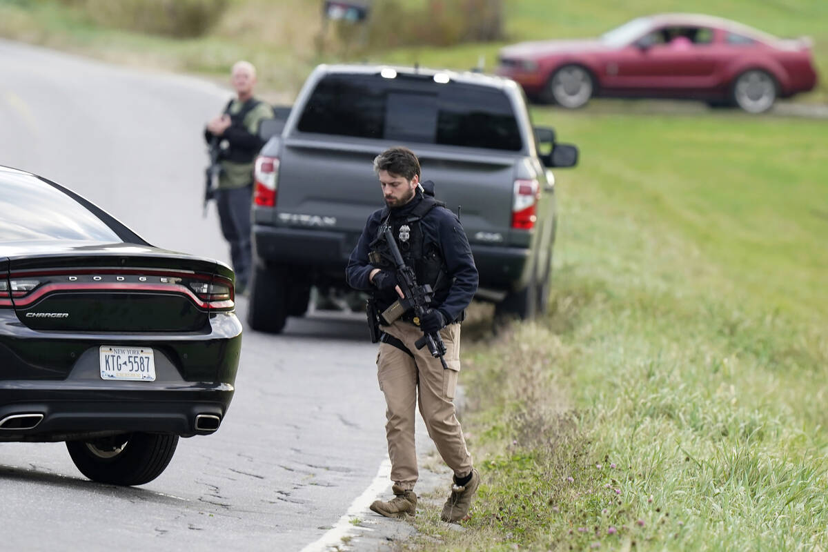 Law enforcement officers hold rifles while investigating a scene, in Bowdoin, Maine, Thursday, ...