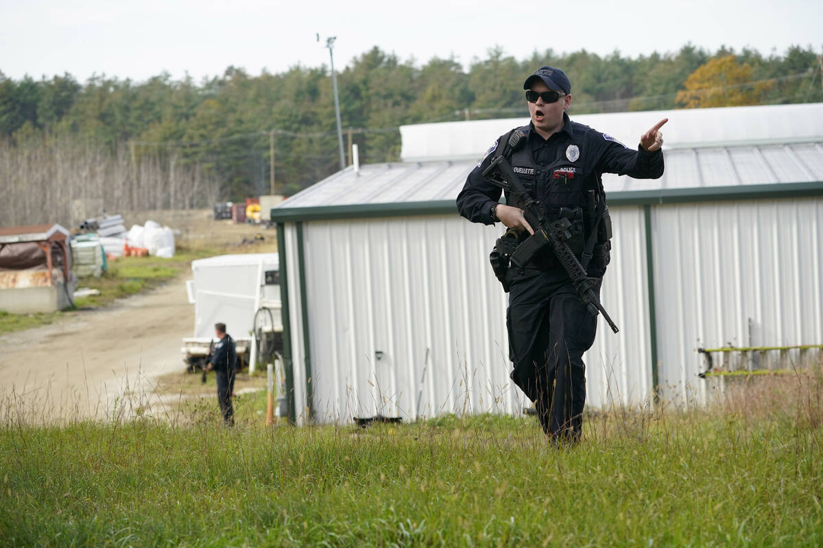 A police officer gives an order to the public during a manhunt at a farm for the suspect in thi ...