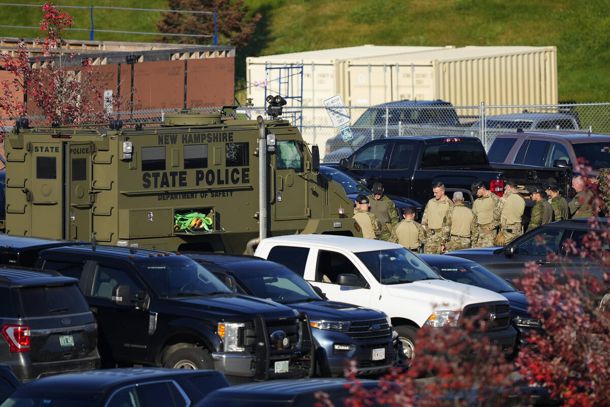 Law enforcement personnel are staged in a school parking lot as a manhunt continues in the afte ...