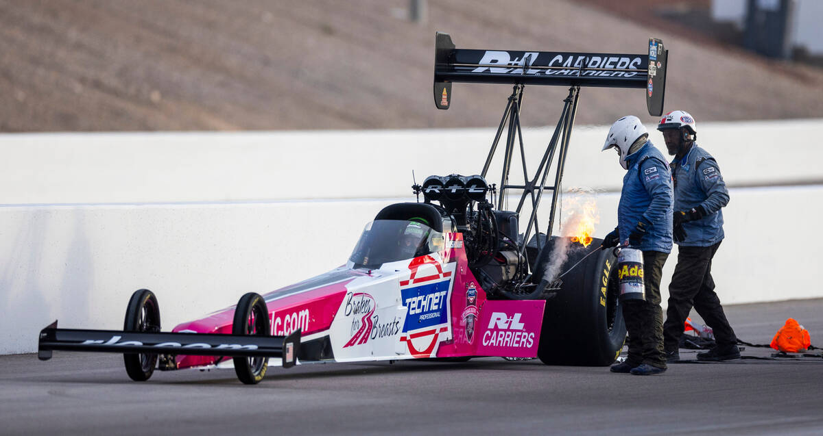 An emergency crew puts out a small fire coming from the car of Top Fuel racer Josh Hart during ...