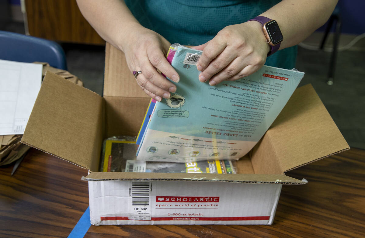 Long STEAM Academy teacher Shana Prue unpacks boxes of school supplies, including books, in her ...