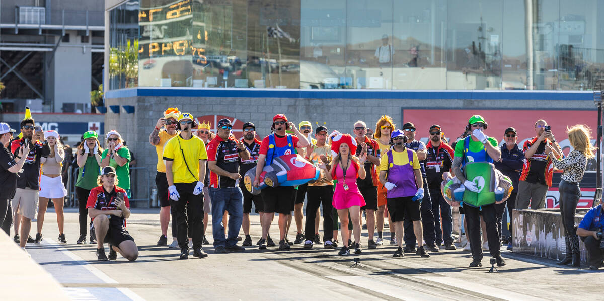 Track personnel and crew members are dressed for Halloween as they watch Pro Stock cars race du ...