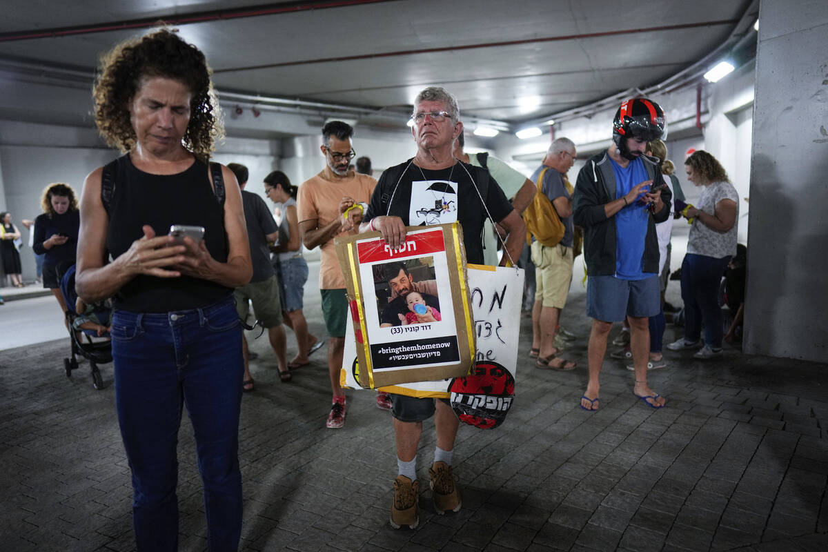 Israelis take cover in an underground car tunnel as a siren warns of incoming rockets fired fro ...