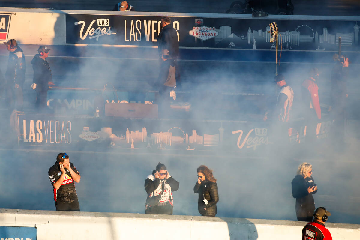 Pit crews and spectators wade through burnout smoke at the NHRA Nevada Nationals at The Strip a ...
