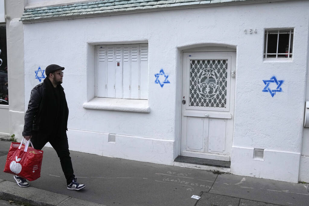 A man walks by Stars of David tagged on a wall in Paris on Tuesday, Oct. 31, 2023. Paris police ...