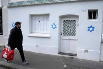 A man walks by Stars of David tagged on a wall in Paris on Tuesday, Oct. 31, 2023. Paris police ...