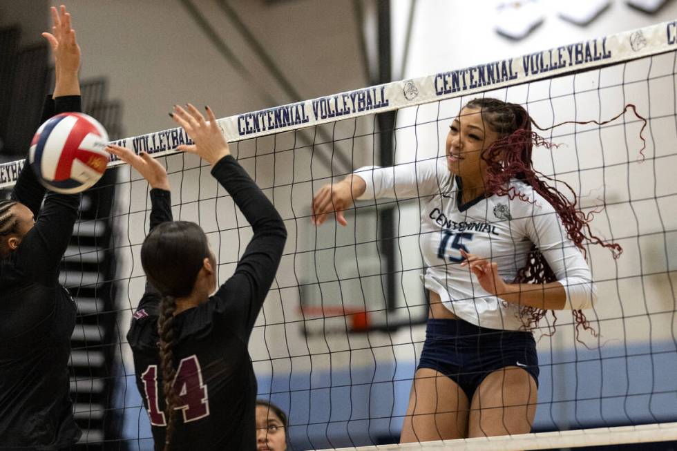 Centennial middle blocker Aliah Williams (15) hits past Faith Lutheran's Sienna Lopez (14) duri ...