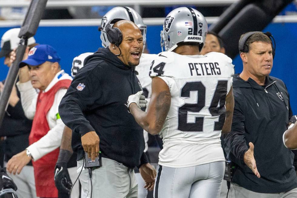 Raiders linebacker coach Antonio Pierce congratulates cornerback Marcus Peters (24) after lineb ...