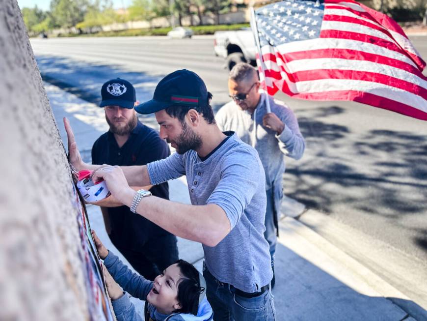 Adam Peniazek, 36, with the help of Akivah G. Bengio, 6, tapes posters of Jewish victims kidnap ...