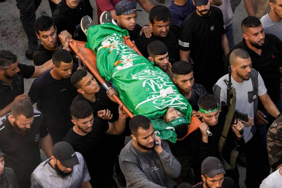 Palestinians carry the bodies of a militant killed in clashes during an Israeli military raid, ...