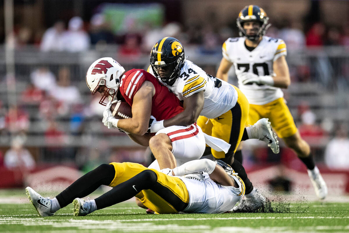 Wisconsin tight end Riley Nowakowski, top left, is brought down by Iowa linebacker Jay Higgins ...