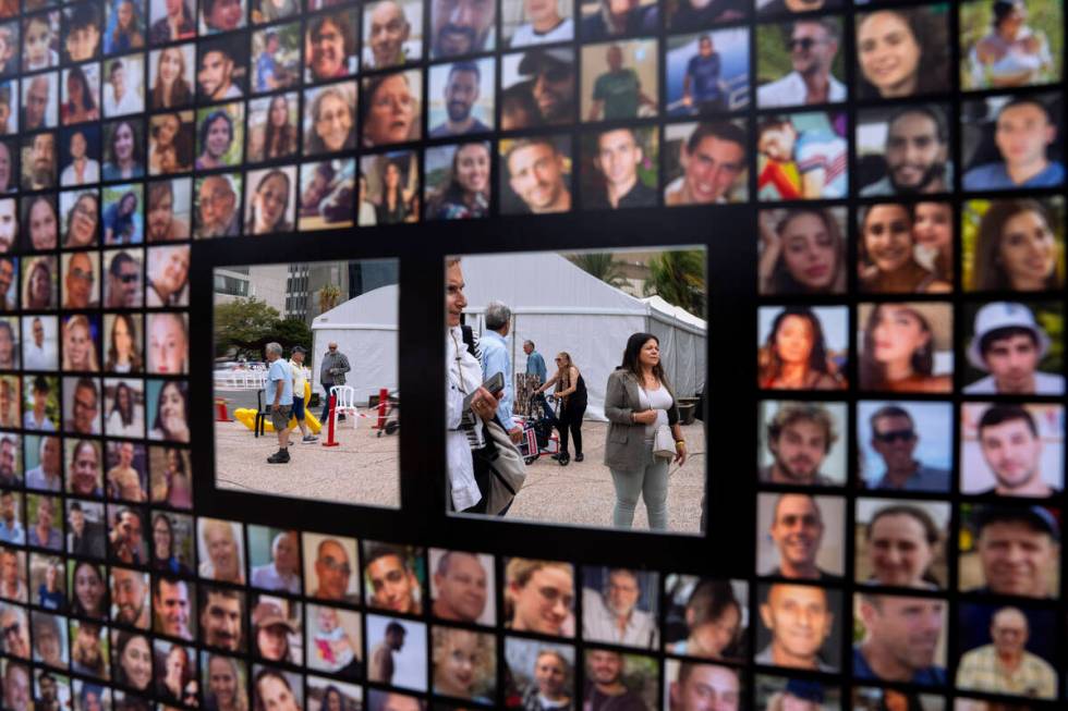 Passersby are reflected by mirrors on a poster with photographs of hostages abducted by Hamas m ...