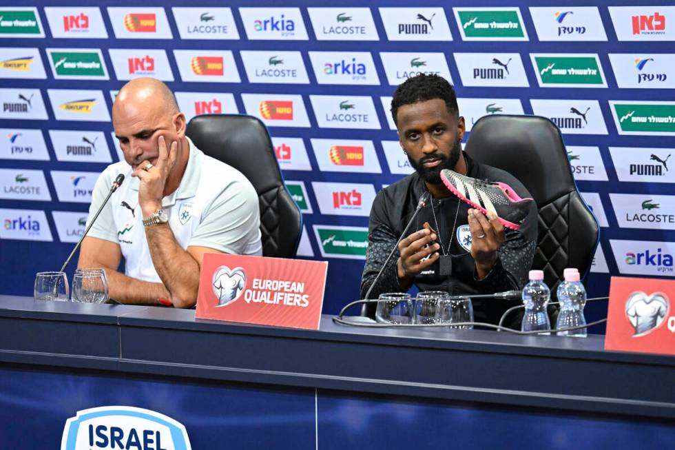 Israel team captain Eli Dasa, right, sits by head coach Alon Hazan as he shows a shoe of a kidn ...