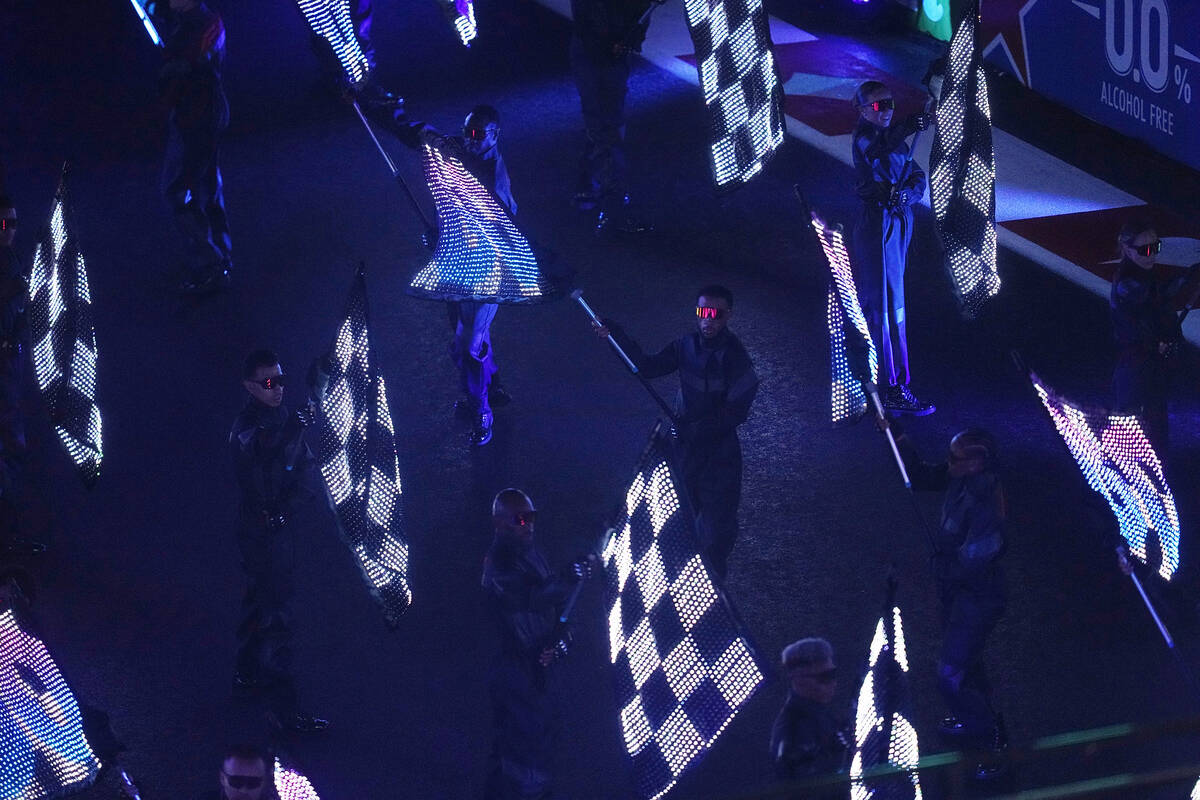 Performers wave flags during an opening ceremony for the Formula One Las Vegas Grand Prix auto ...