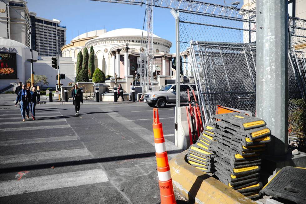 Pedestrians cross the Strip near equipment for the Formula 1 Las Vegas Grand Prix race on the S ...