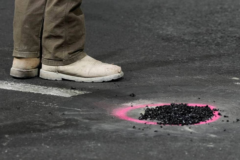 A worker stand by a hole that was repaired before the second practice session for the Formula O ...