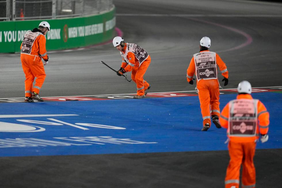 Workers pick up debris from the track after a crash during the Formula One Las Vegas Grand Prix ...